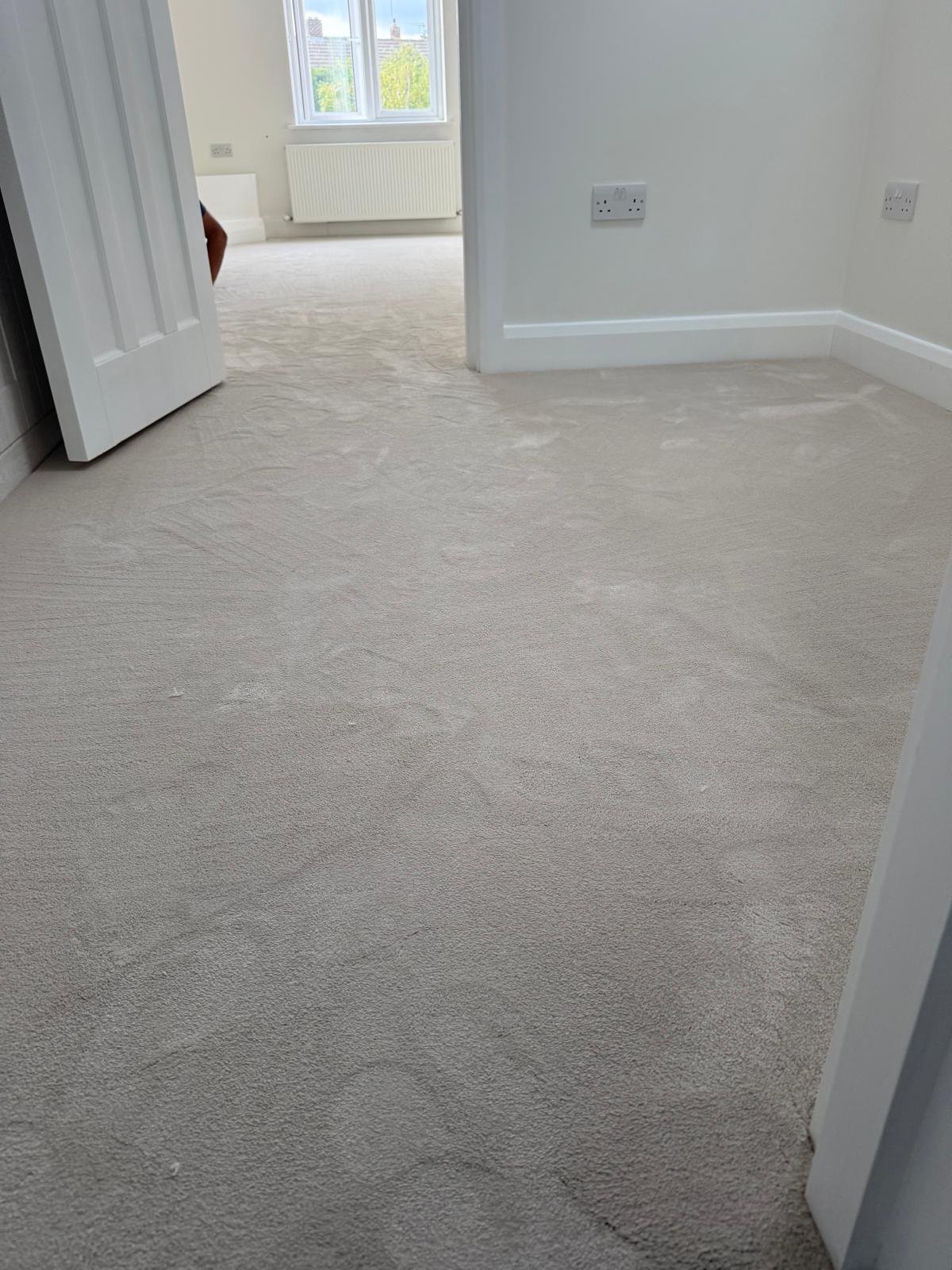 Pale cream carpet in a bright empty bedroom with white skirtings and a radiator under the window